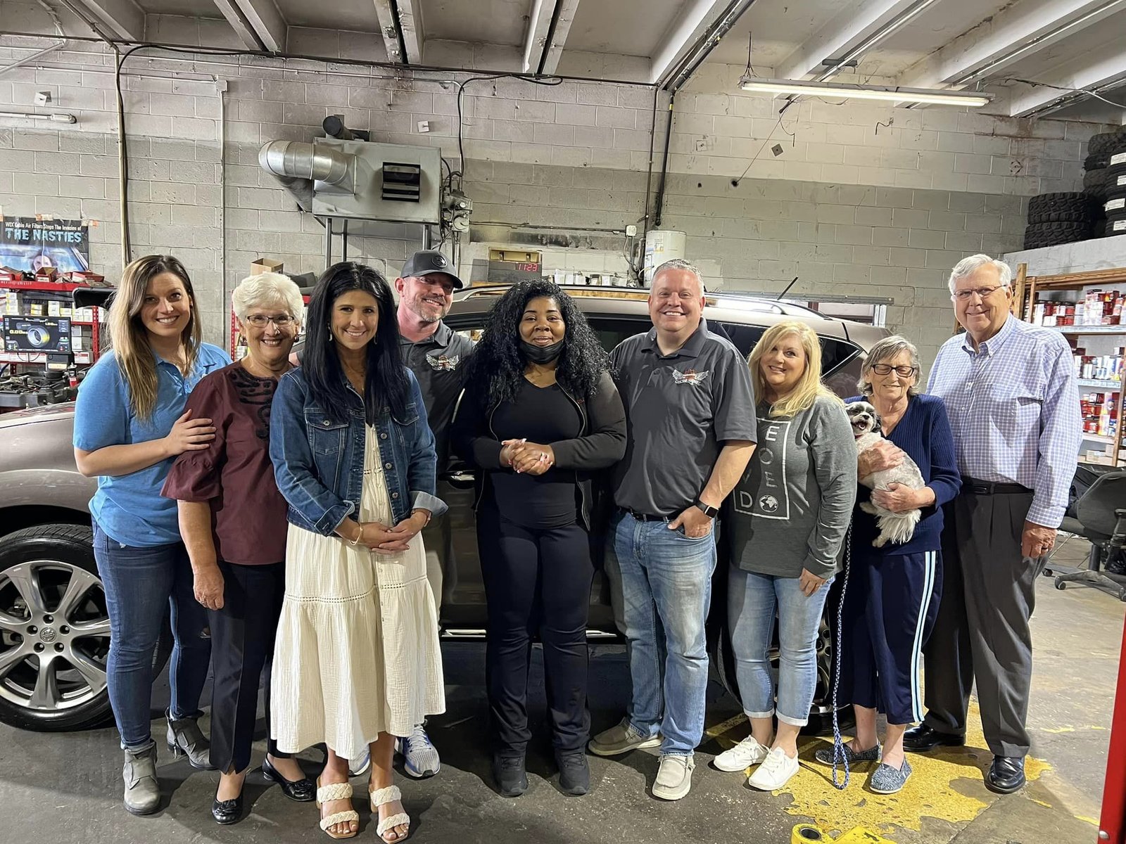 Volunteers and a family in the Mechanics on a Mission shop beside a donated vehicle