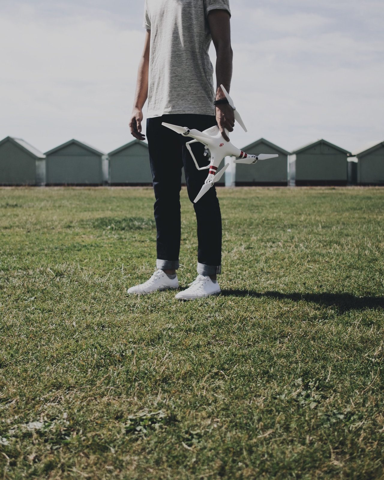A drone pilot holding a drone in a field