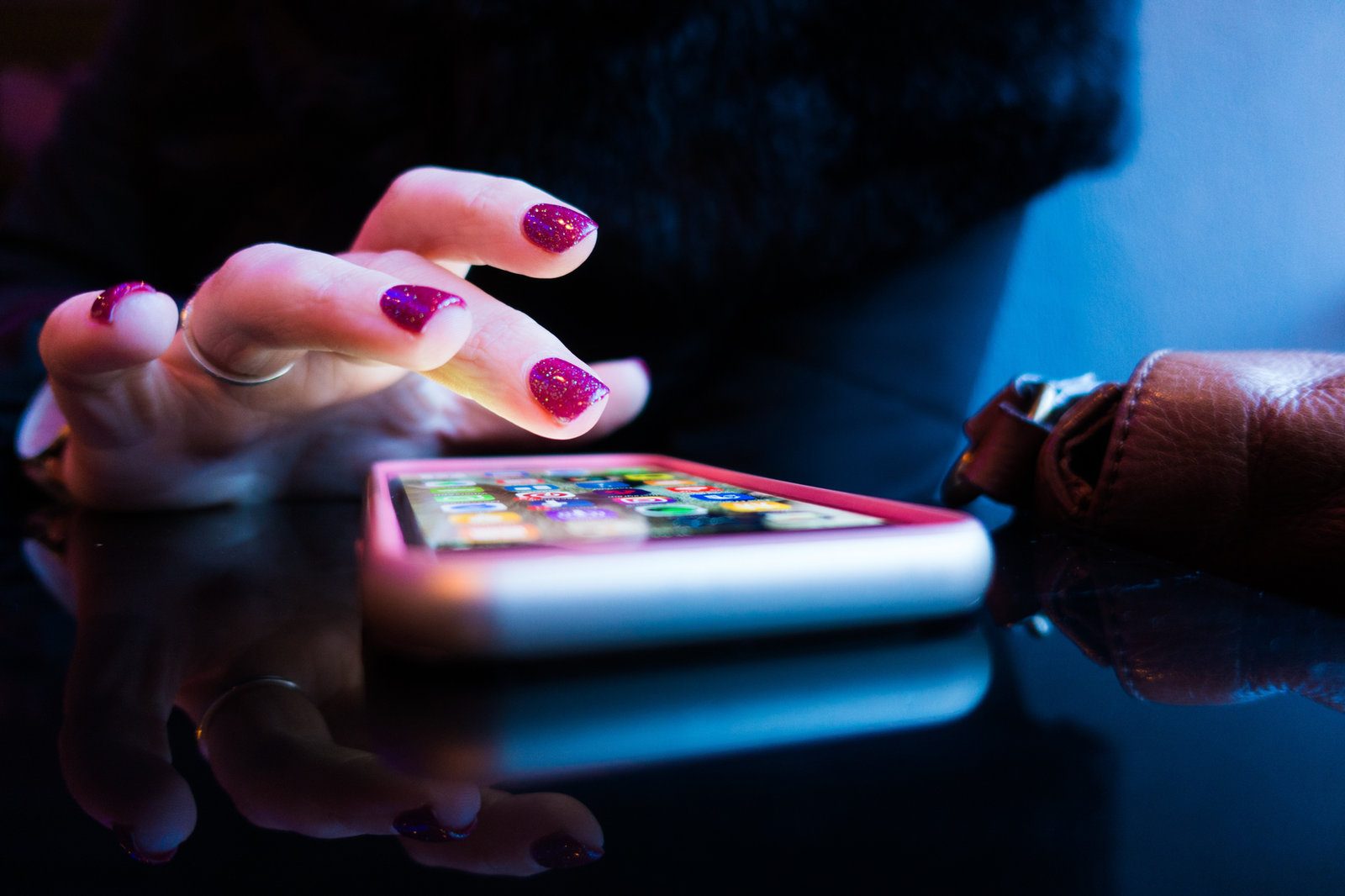 A hand scrolling a phone lit in blue